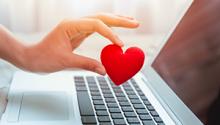 Woman's hand holding a heart over a laptop keyboard. West Financial Services
