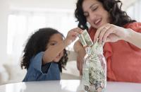 Mother teaching daughter to save using a jar. West Financial Services