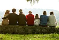 Seven multi generational family members sitting on a stone fence and looking over the valley. West Financial Services