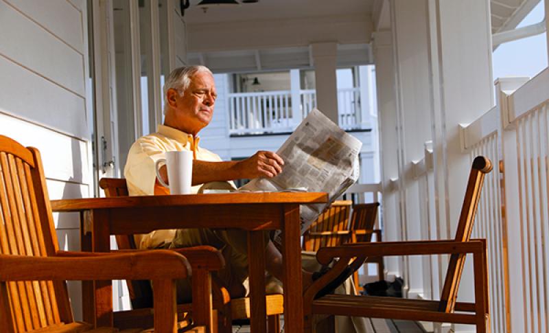 Man reading paper on front porch. West Financial Services.
