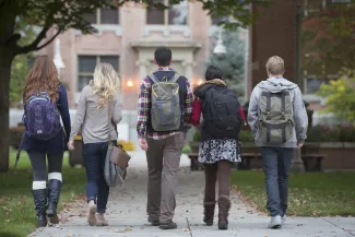 Students walking towards a college building. West Financial Services