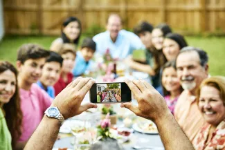 Family sitting around a picnic table and taking a picture. West Financial Services.