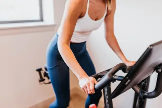 Women riding a stationary bike. West Financial Services.
