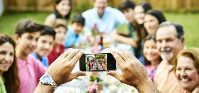 Family sitting around a picnic table and taking a picture. West Financial Services.