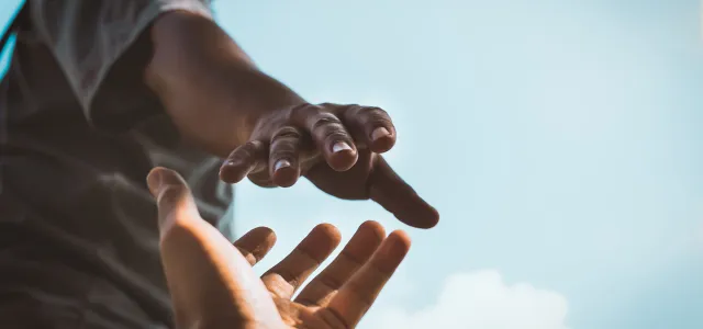 One hand reaching out to grasp another hand. West Financial Services.