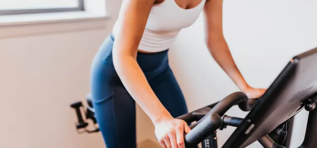 Women riding a stationary bike. West Financial Services.